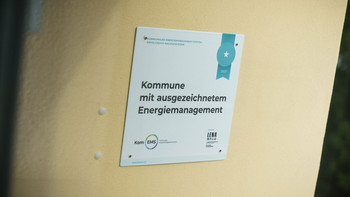 Nahaufnahme des Schildes mit der Aufschrift "Kommune mit ausgezeichnetem Energiemanagement"