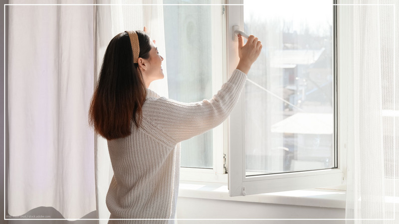 Eine Frau öffnet ein Fenster zur Raumlüftung